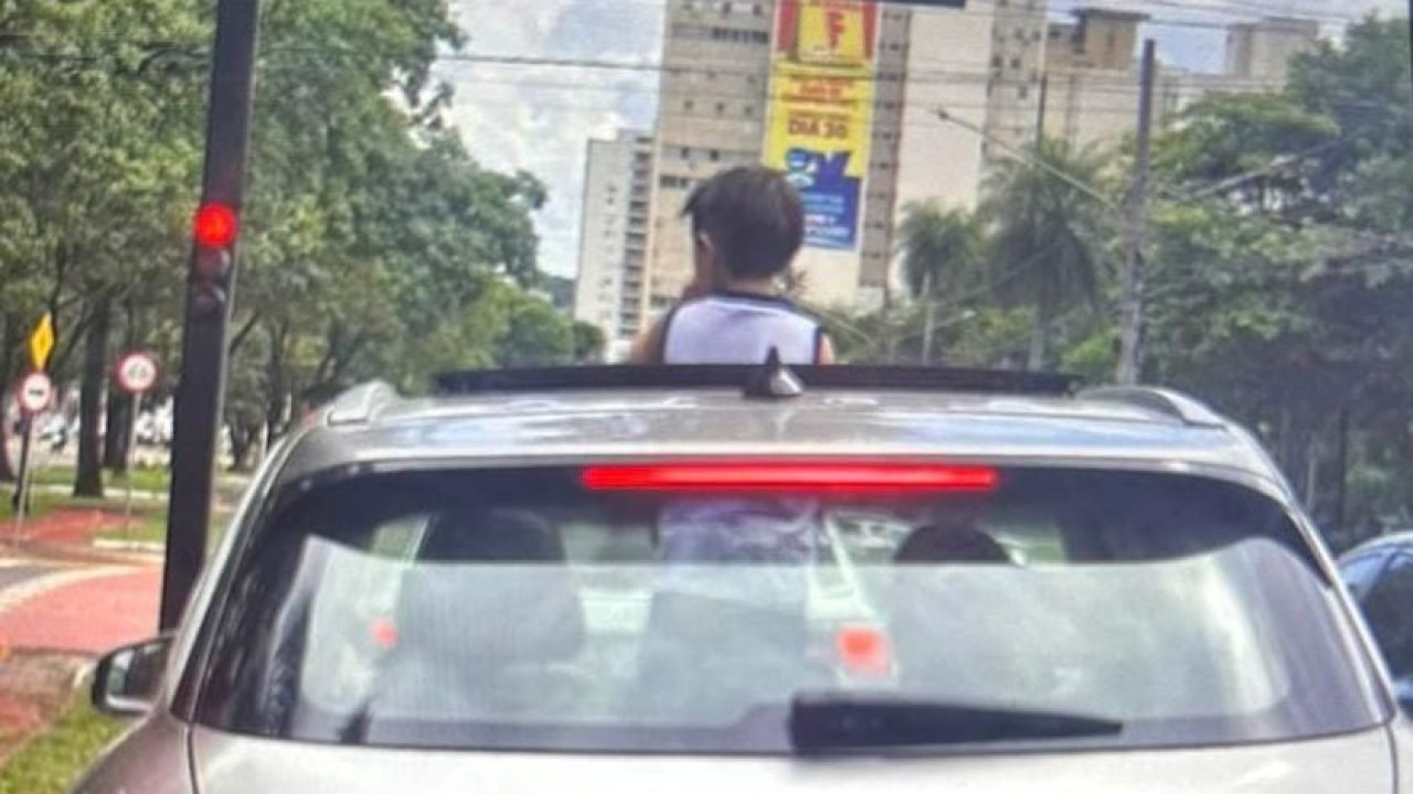 Foto: Motorista levou criança com o corpo para fora do teto solar do carro. (Fot