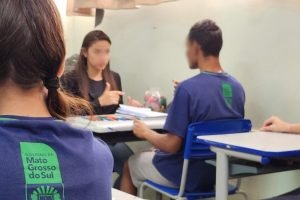 Professora de apoio auxilia aluno atípico durante aula em escola estadual. — Fot