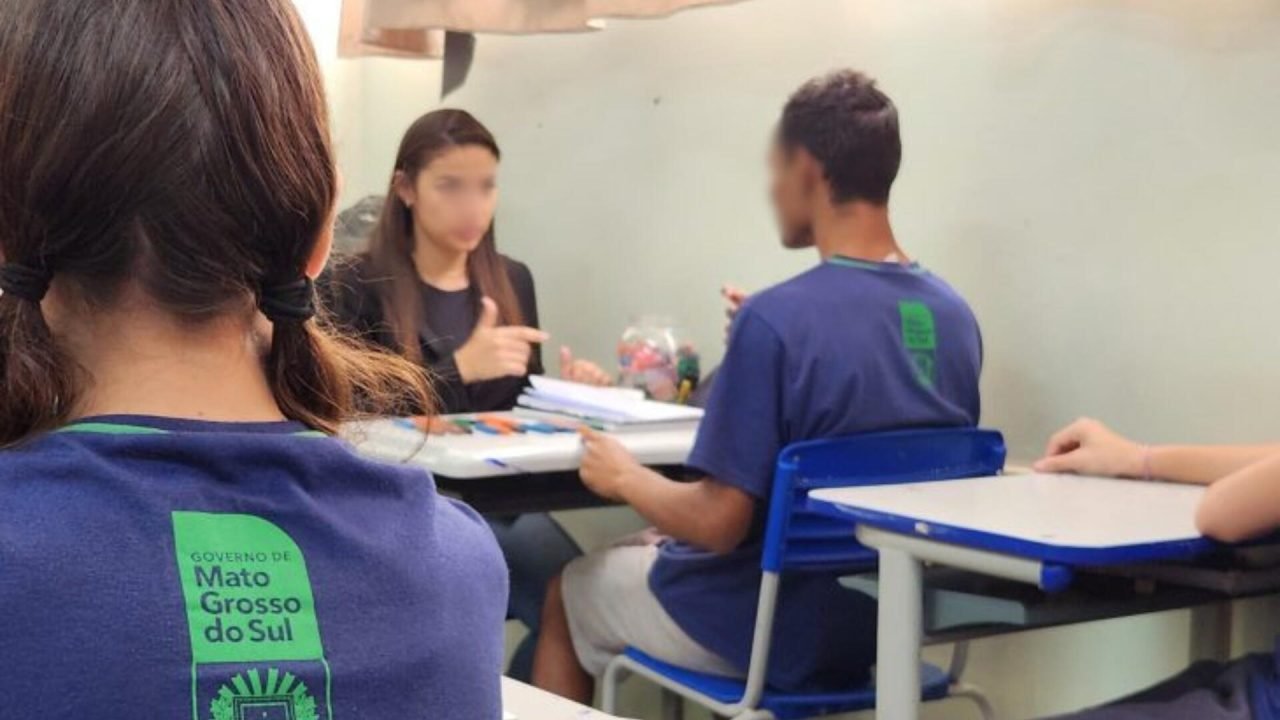 Professora de apoio auxilia aluno atípico durante aula em escola estadual. — Fot