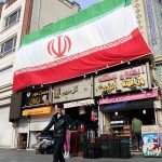Foto: Um homem iraniano fala ao celular enquanto caminha ao lado de uma enorme b