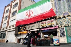 Foto: Um homem iraniano fala ao celular enquanto caminha ao lado de uma enorme b