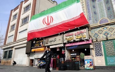 Foto: Um homem iraniano fala ao celular enquanto caminha ao lado de uma enorme b