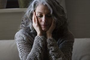 mulher-mais-velha-triste-no-sofa-scaled-1